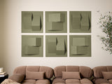 Six sage green dimensional tiles with geometric cutout patterns arranged in a grid on a wall above a tan sectional sofa.