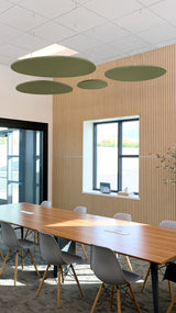 Four sage green oval acoustic baffles suspended from ceiling above wooden conference table in office space.