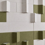 3D geometric wall panels with a textured finish in off-white and olive green, arranged in a staggered block pattern.