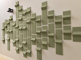 Sage green dimensional tiles arranged in staggered pattern on wall with varying depths and protrusions.