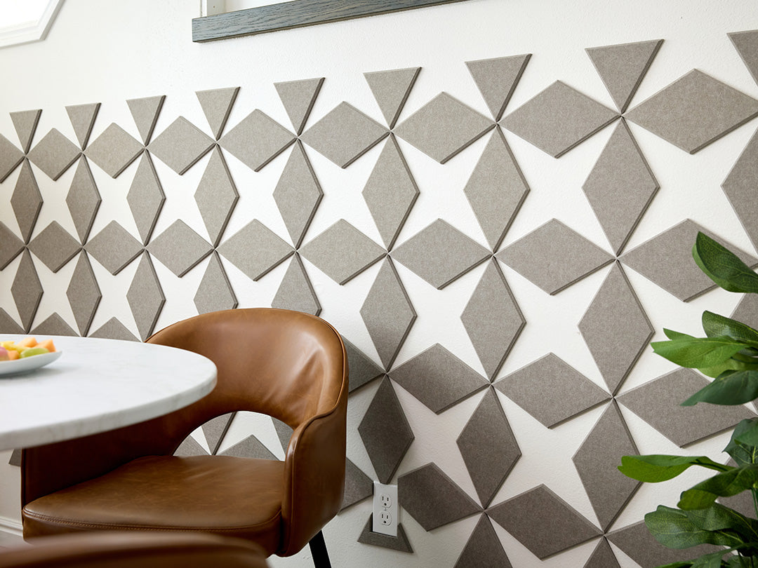 Geometric patterned wall panels in a room with a chair and table.