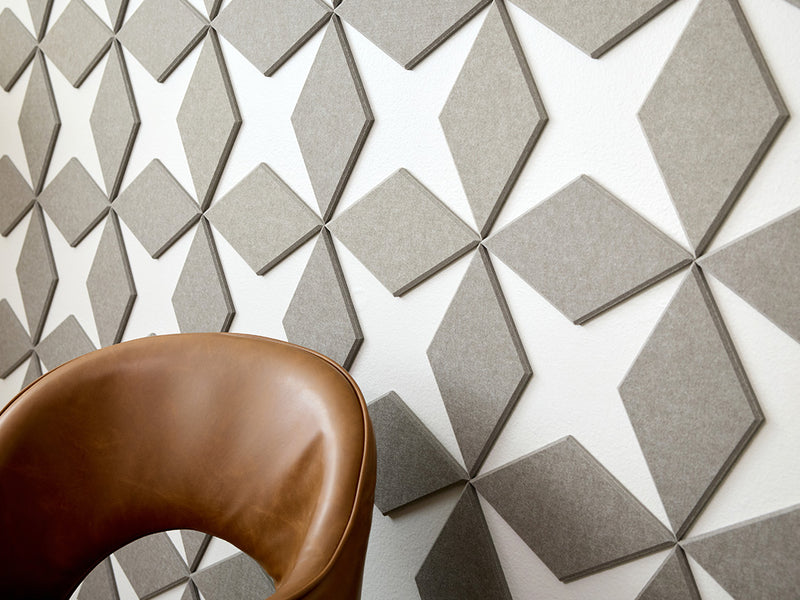 Geometric patterned wall tiles with a brown chair in the foreground