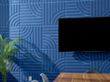 Blue geometric wallpaper with layered linear and curved patterns, green potted plant visible on left side.