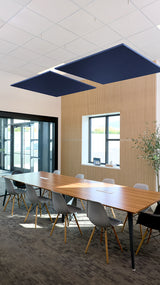 Two navy blue square acoustic baffles suspended from white ceiling grid above conference table.
