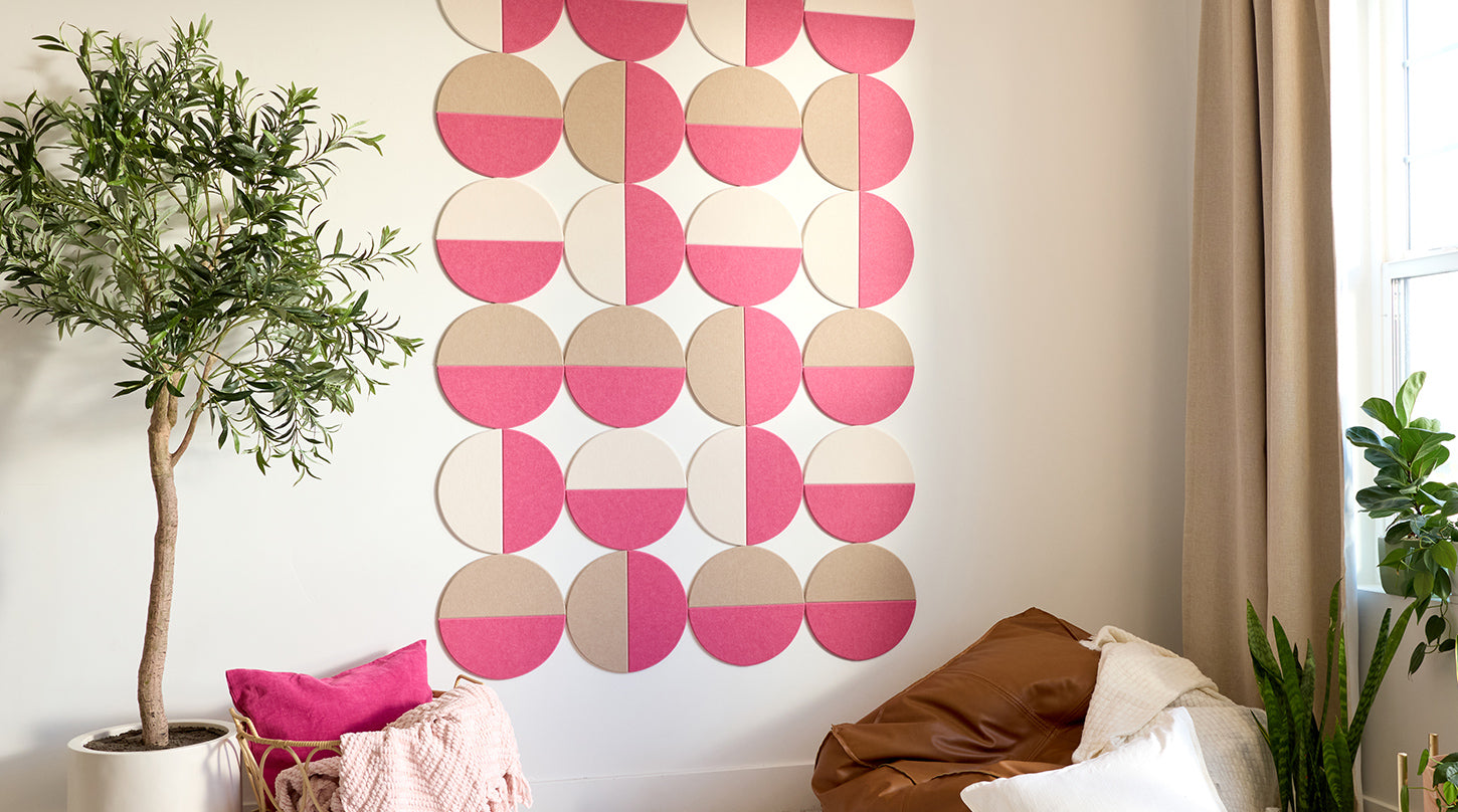 Decorative acoustic wall art with pink and beige circles in a room with plants and furniture.