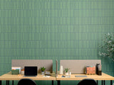 Green vertical ribbed tile wall behind wooden desk with office supplies and potted plants.