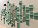 Green 3D dimensional tiles arranged in staggered pattern on white wall with varying depths and angles.