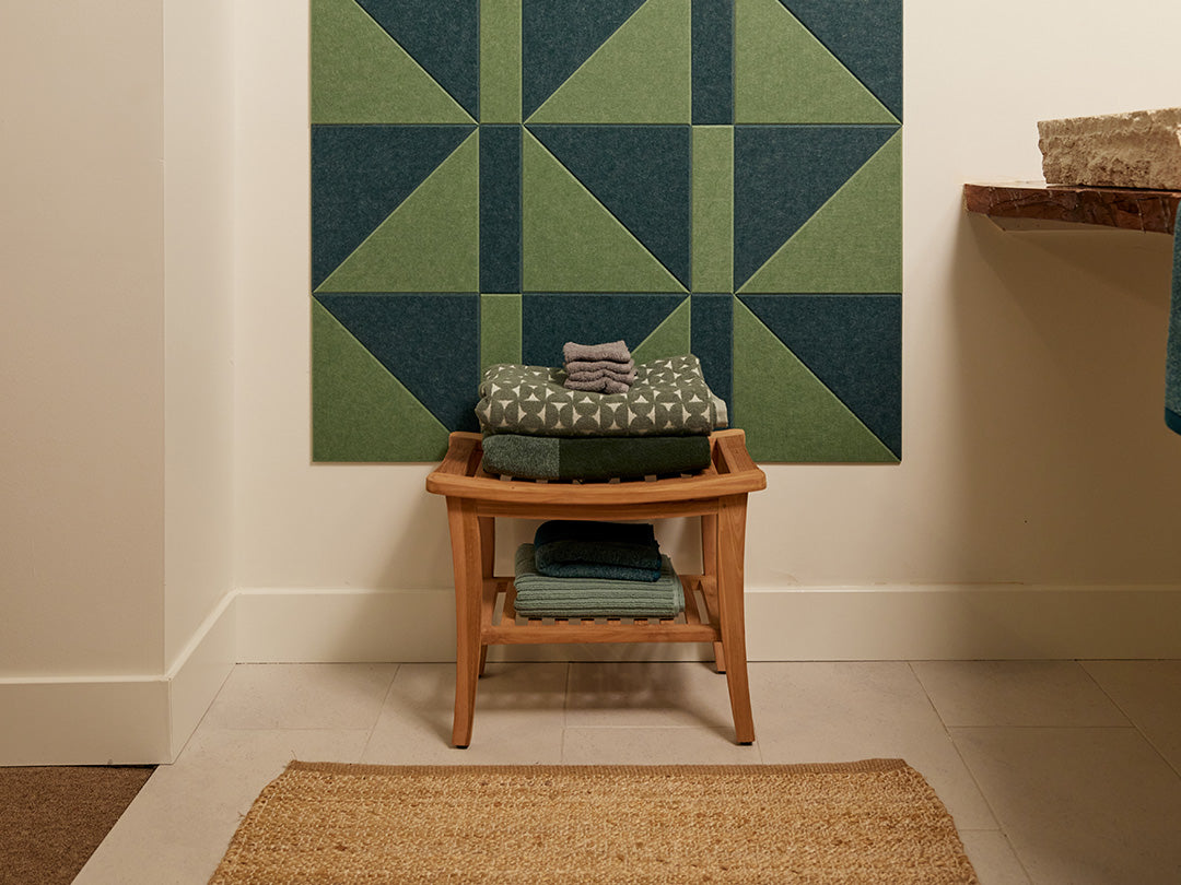 Felt Right wall art in shades of green felt tiles on a wall with a stool holding towels in a bathroom