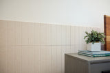 Beige 2'x2' tiles with vertical engraved parallel lines installed on wall behind furniture.