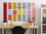 Pastel rainbow pinstripe bulletin board with daily schedule cards and colorful pom-pom garland decoration.