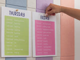 Bulletin board with vertical pastel pinstripes in blue, gray, purple, pink, and peach behind two weekly schedule cards.