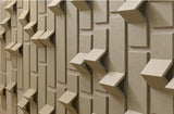 Beige dimensional tiles with geometric chevron and rectangular raised patterns creating depth and shadow.
