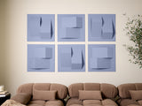 Six blue-gray tiles with layered geometric shapes and shadows arranged in a grid above a tan sofa.