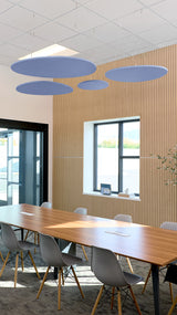 Four blue cloud-shaped ceiling baffles suspended above a conference table in an office space.