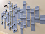 Blue-gray dimensional wall tiles in varying heights and depths arranged in geometric pattern on beige wall.