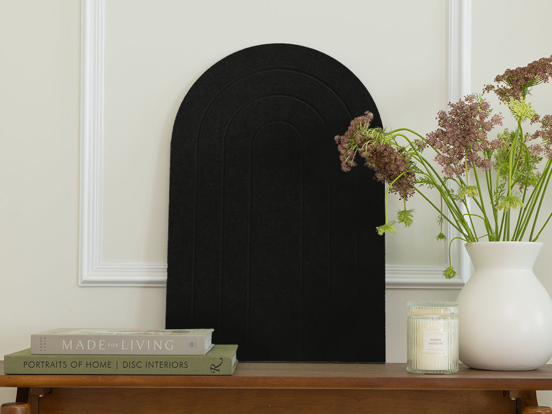 Black decorative arch on a wooden table with books and a vase of flowers.