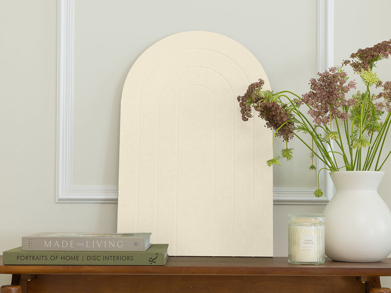 Decorative mirror on a wooden table with books and a vase of flowers.