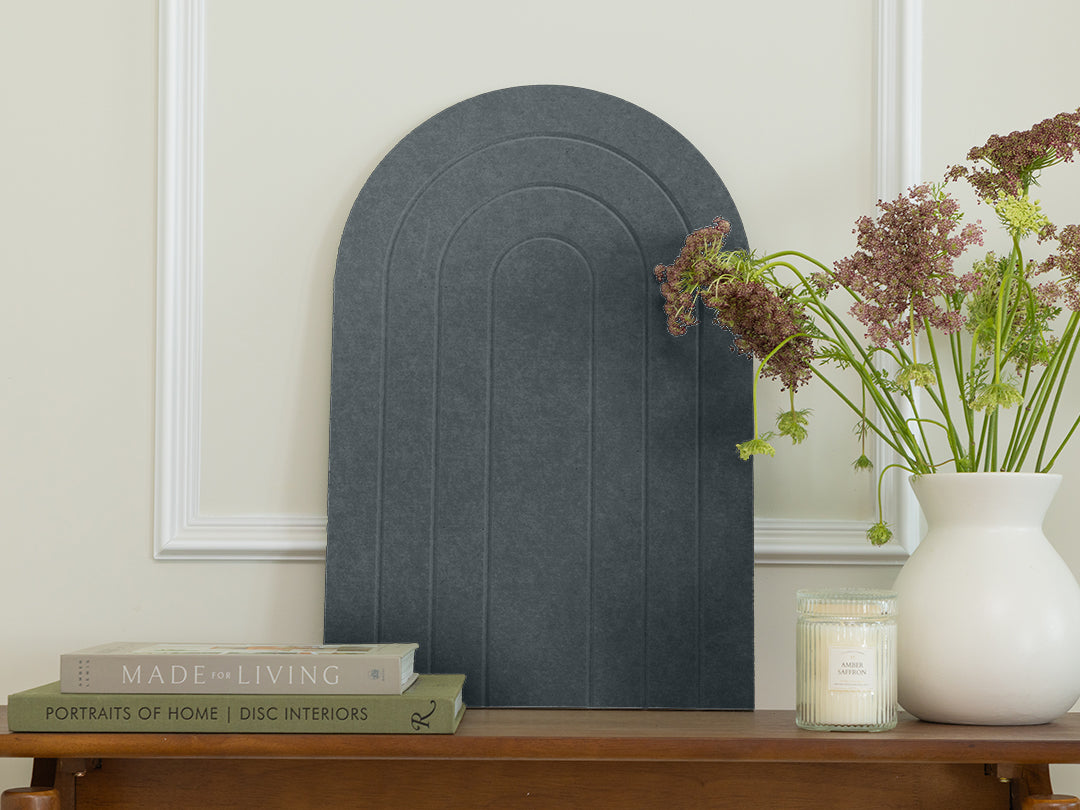 Decorative arch-shaped object on a wooden table with books and a vase of flowers.