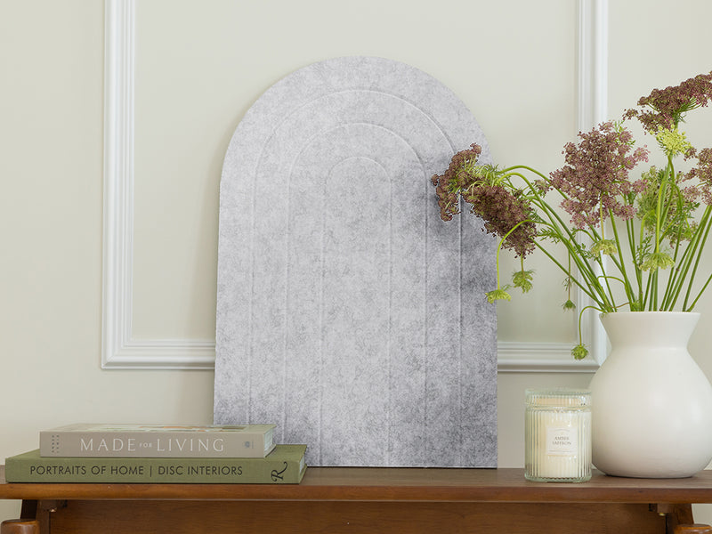 Decorative mirror on a wooden console table with books and a vase of flowers.