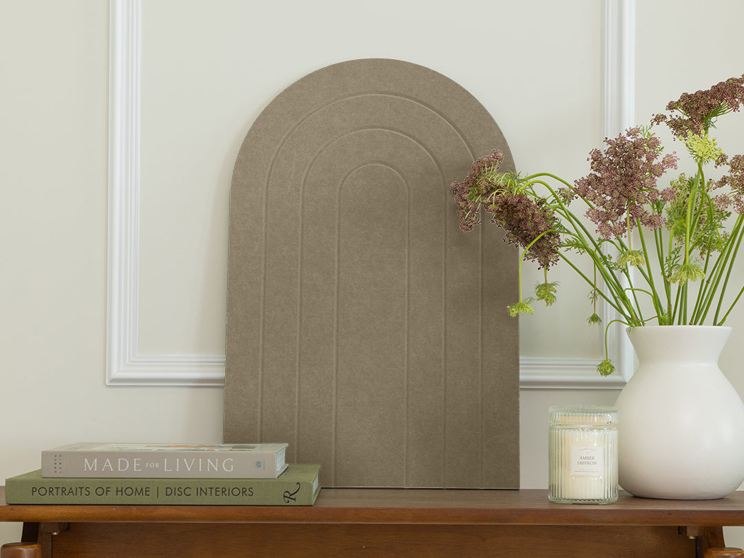 Decorative arch on a wooden table with books and a vase of flowers.