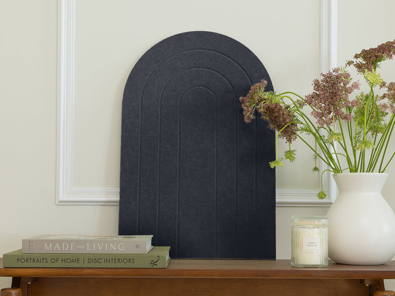 Decorative black arch on a wooden table with books and a vase of flowers.