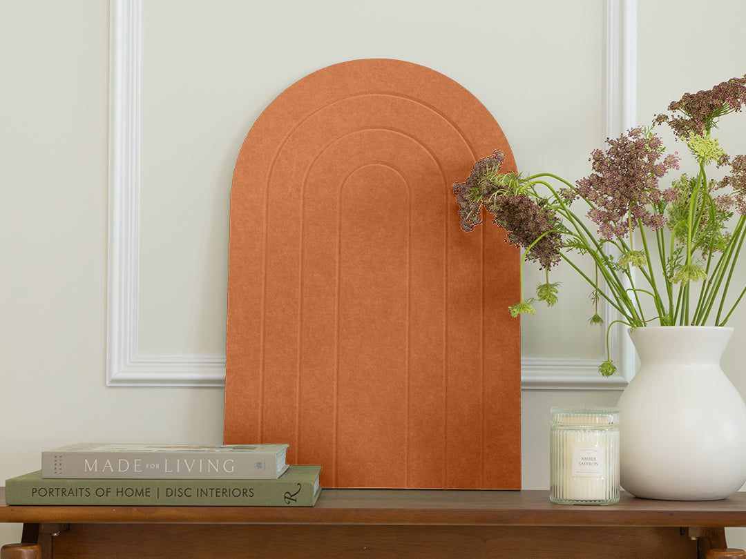 Decorative arch on a table with books, a candle, and a vase of flowers.