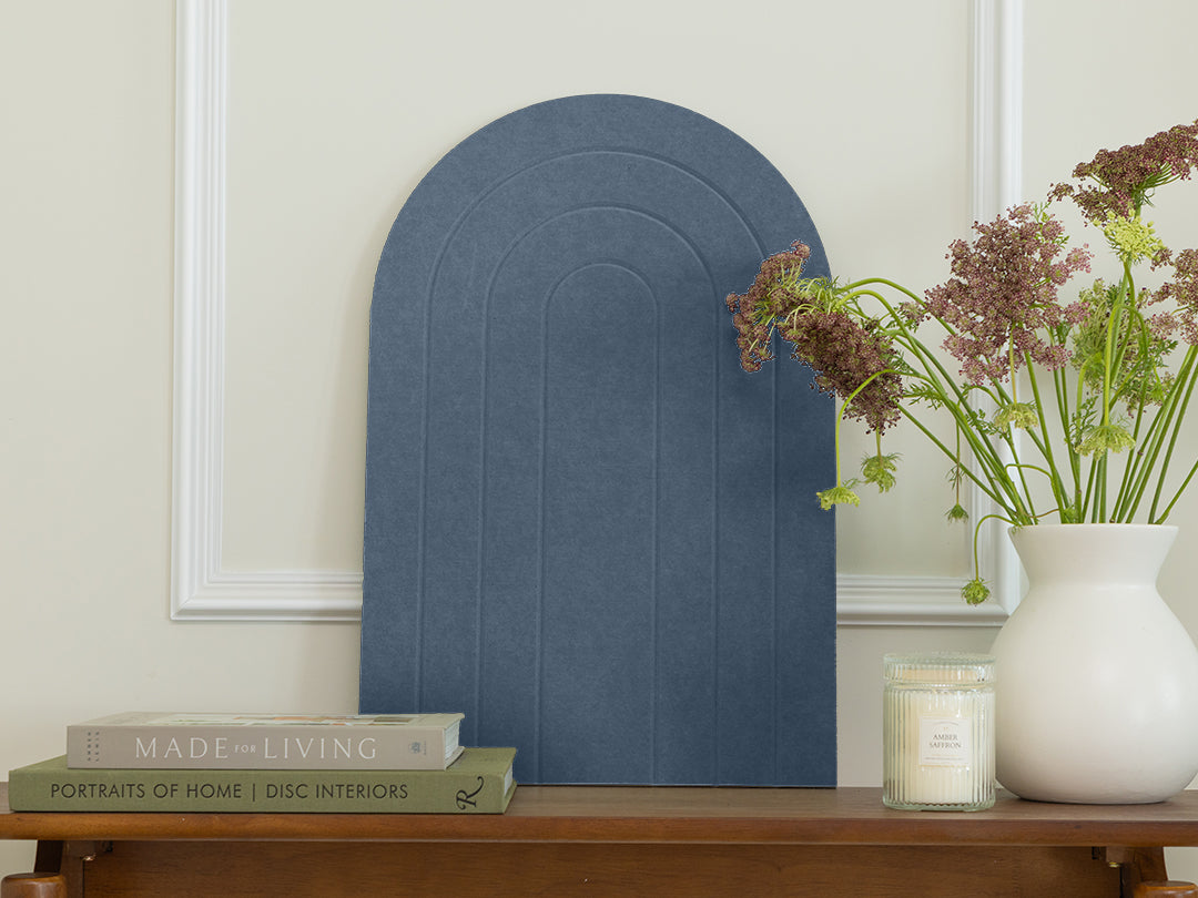 Decorative blue wall art piece on a wooden shelf with books and a vase.