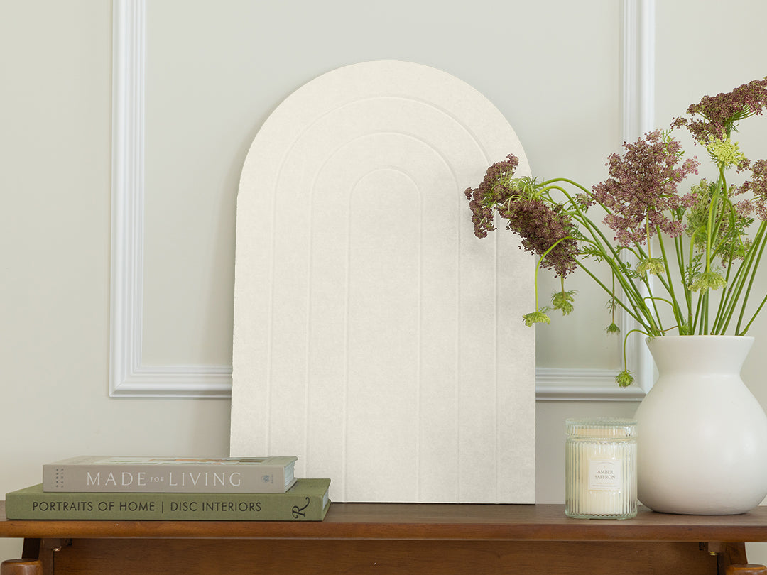 Decorative mirror on a wooden table with books and a vase of flowers.