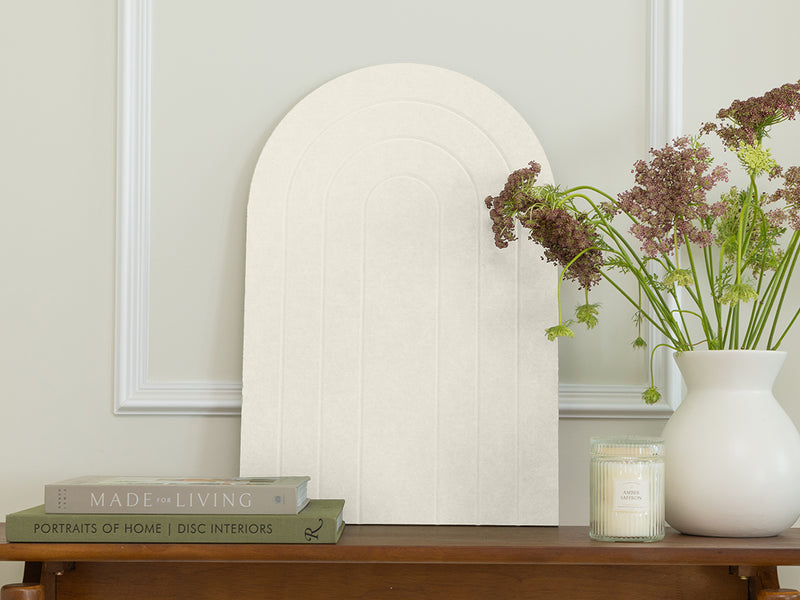 Decorative mirror on a wooden table with books and a vase of flowers.