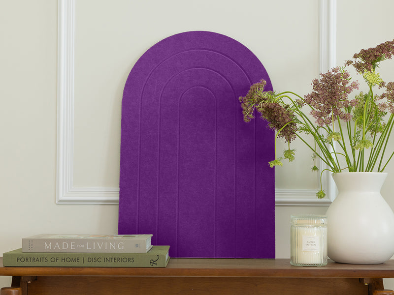 Purple decorative arch on a wooden table with books and a vase of flowers.