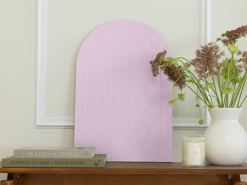 Decorative pink arch on a wooden table with books and a vase of flowers.