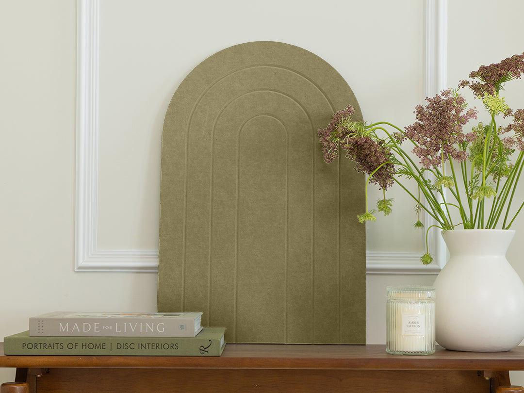 Decorative wall art piece on a wooden table with books and a vase.