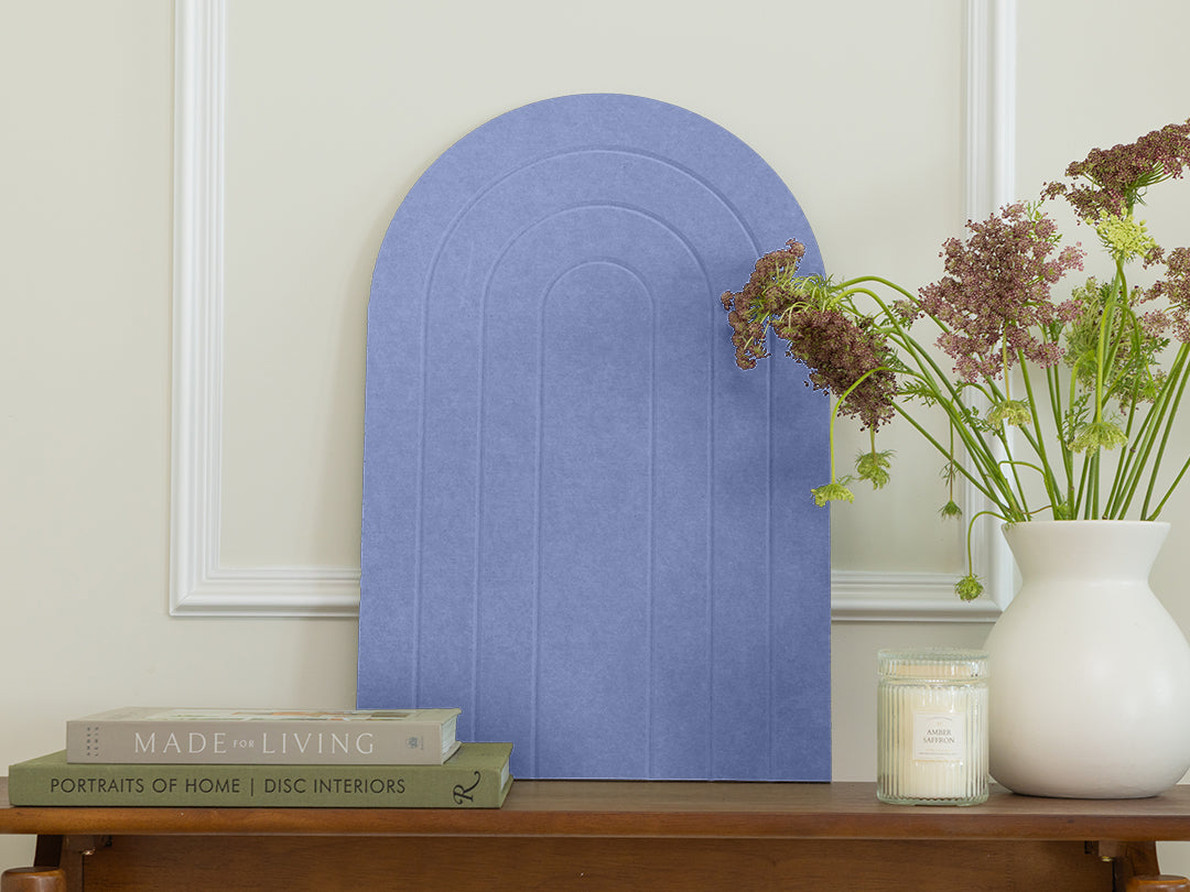 Decorative blue arch on a wooden table with books and a vase of flowers.