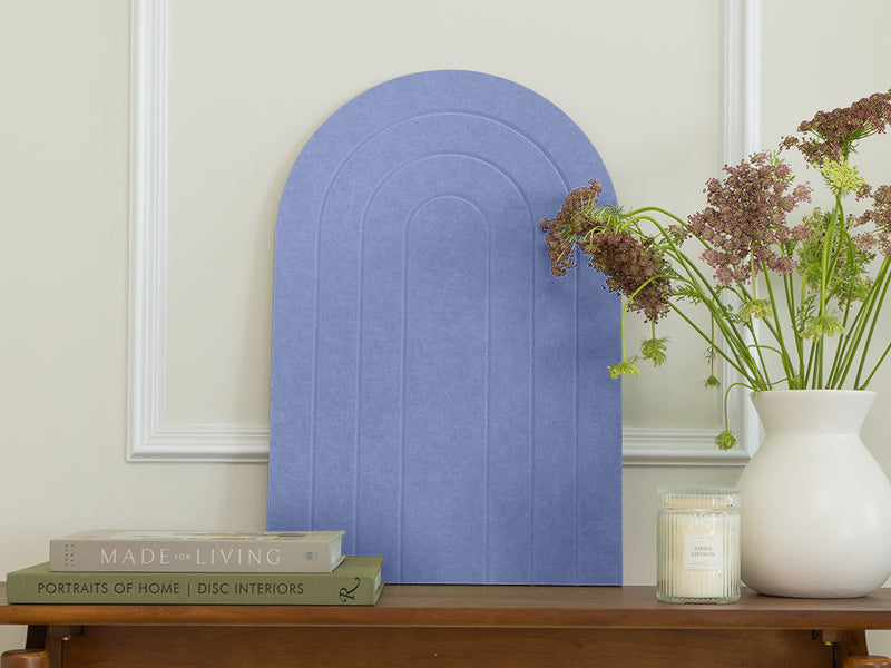 Decorative blue arch on a wooden table with books and a vase of flowers.