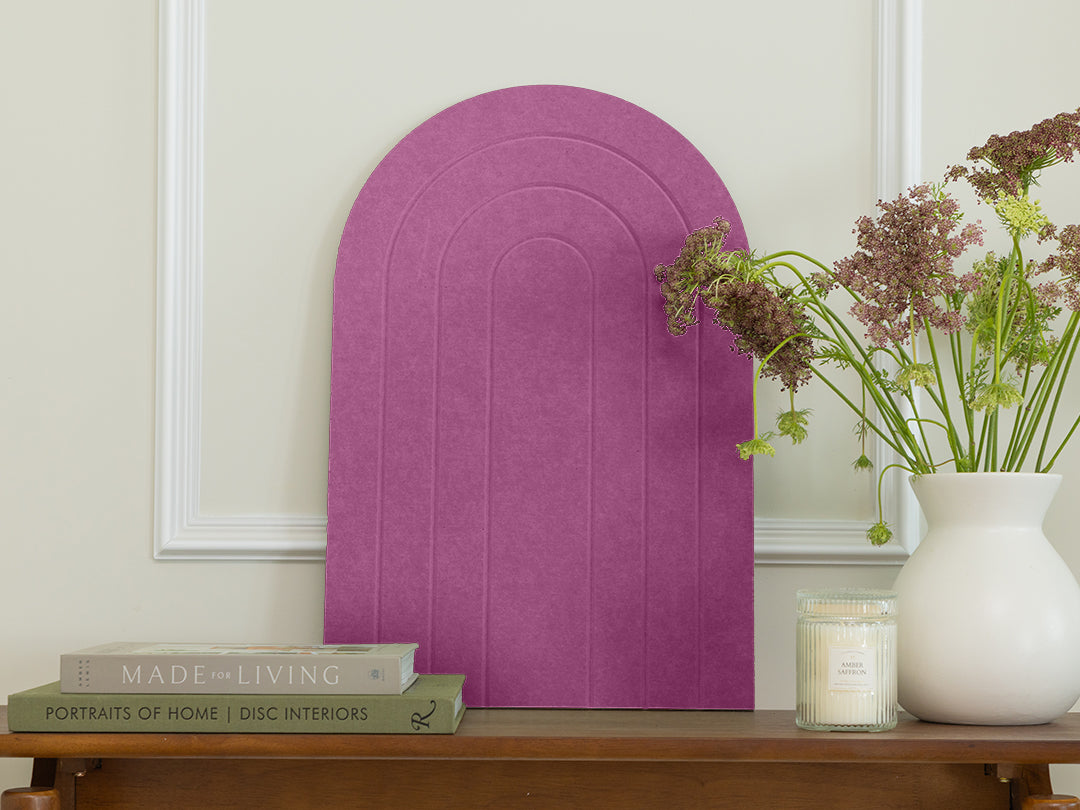 Purple arch-shaped headboard on a wall with books and a vase on a wooden surface.