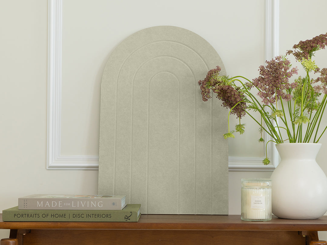 Decorative mirror on a wooden table with books and a vase of flowers.