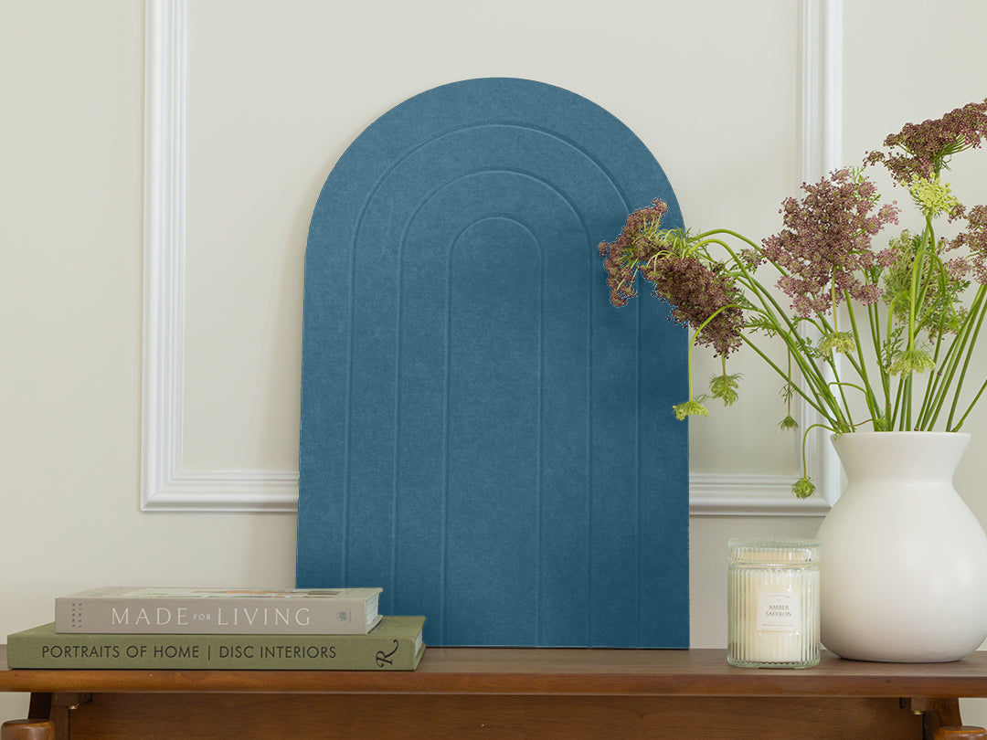 Blue arch-shaped decorative item on a wooden table with books and a vase.