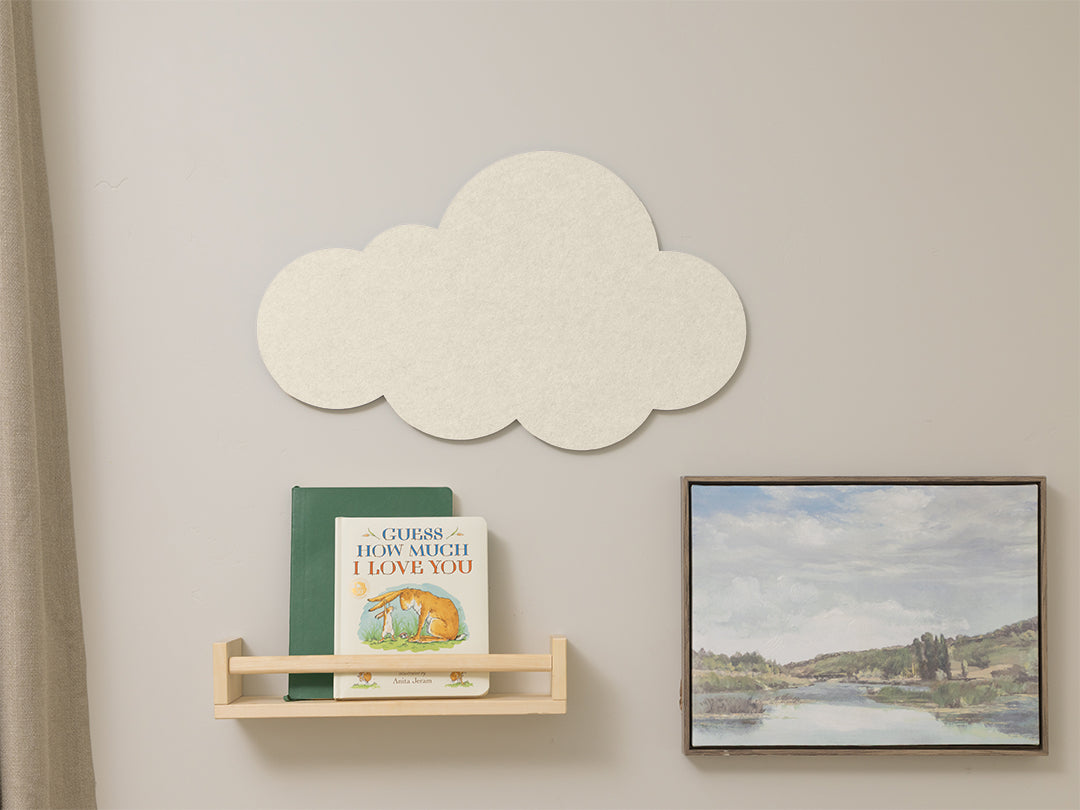 Cloud-shaped decorative item on a wall with a book and framed picture below.