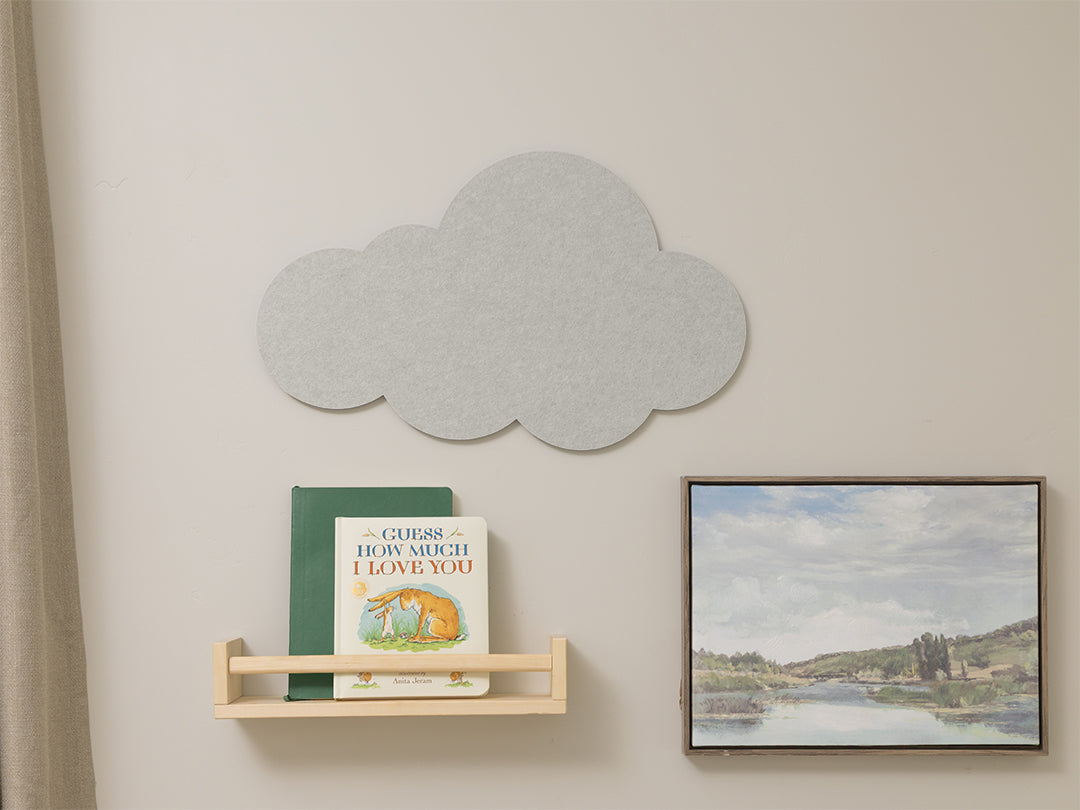 Cloud-shaped decorative wall panel on a light gray wall with a shelf and framed picture.