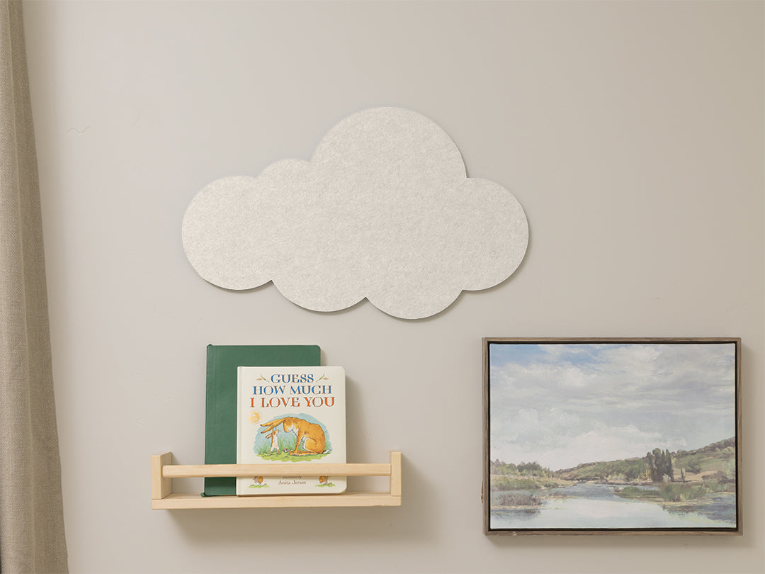 Cloud-shaped decorative wall panel on a light gray wall with a shelf and framed picture.