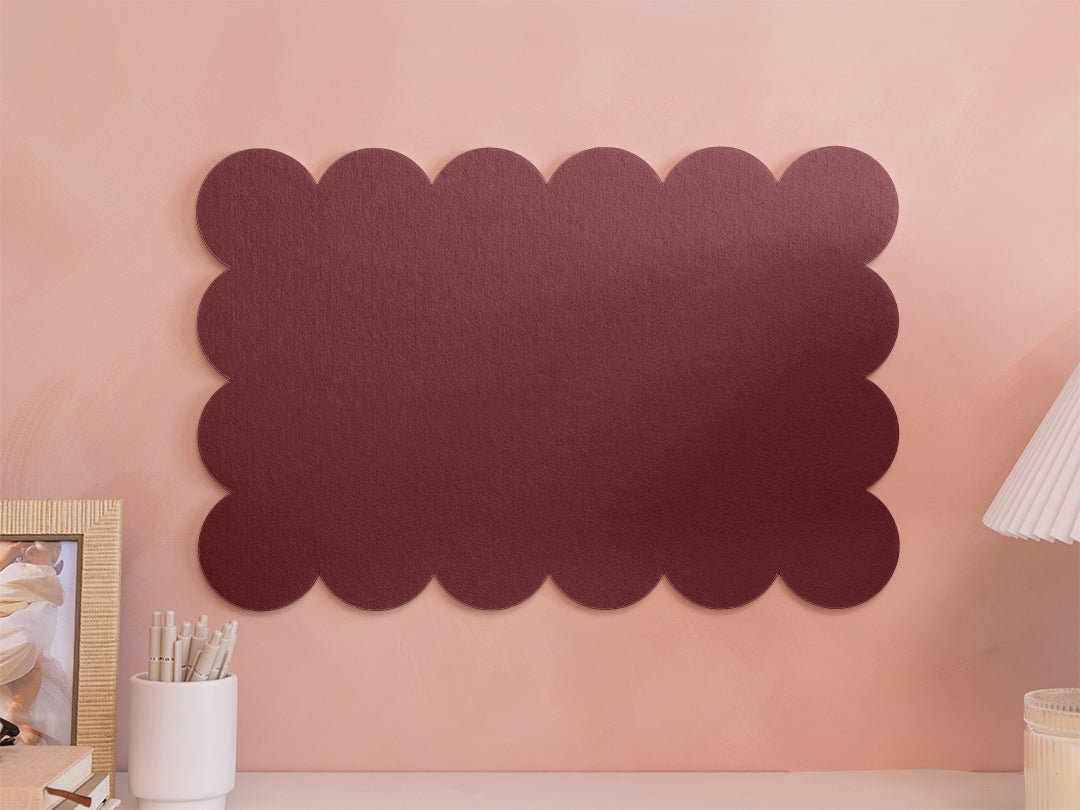 Decorative dark brown wall art on a pink wall with a lamp and photo frame in the background.
