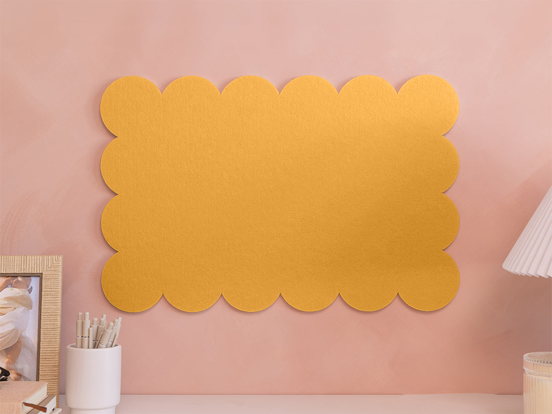 Yellow scalloped wall panel on a pink wall with decor items.