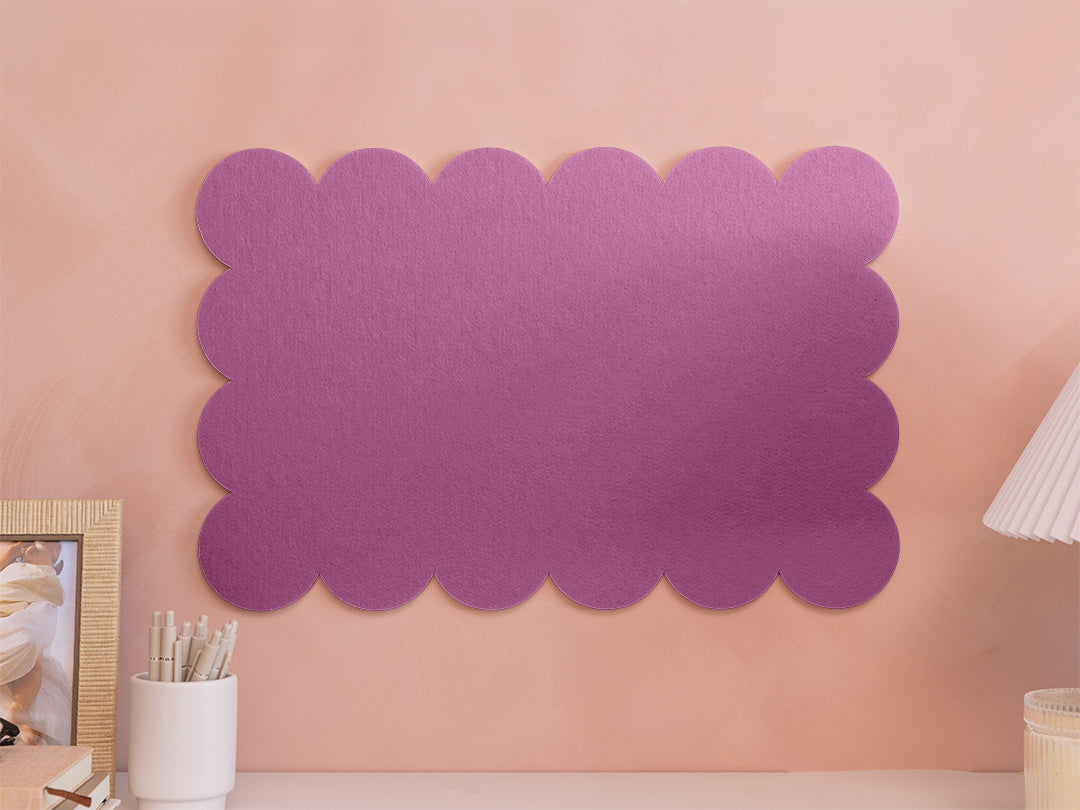 Purple scalloped wall art on a pink wall with decor items.