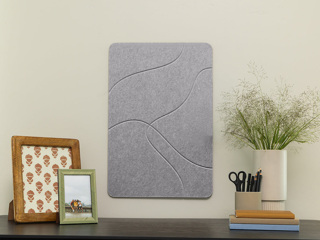 Gray textured wall panel on a white wall with decorative items below.