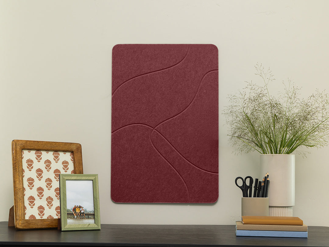 Wine red felt wall panel with wavy topo pattern on a shelf with decorative frames and plant