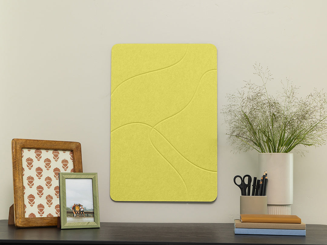 Yellow textured wall panel on a white wall with decorative items below.