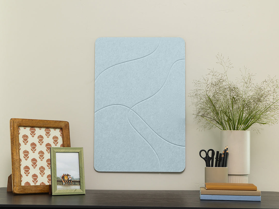 Decorative wall panel with a wavy pattern on a shelf with picture frames and a plant.