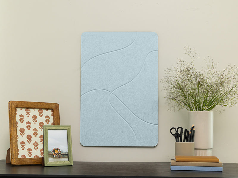 Decorative wall panel with a wavy pattern on a shelf with picture frames and a plant.