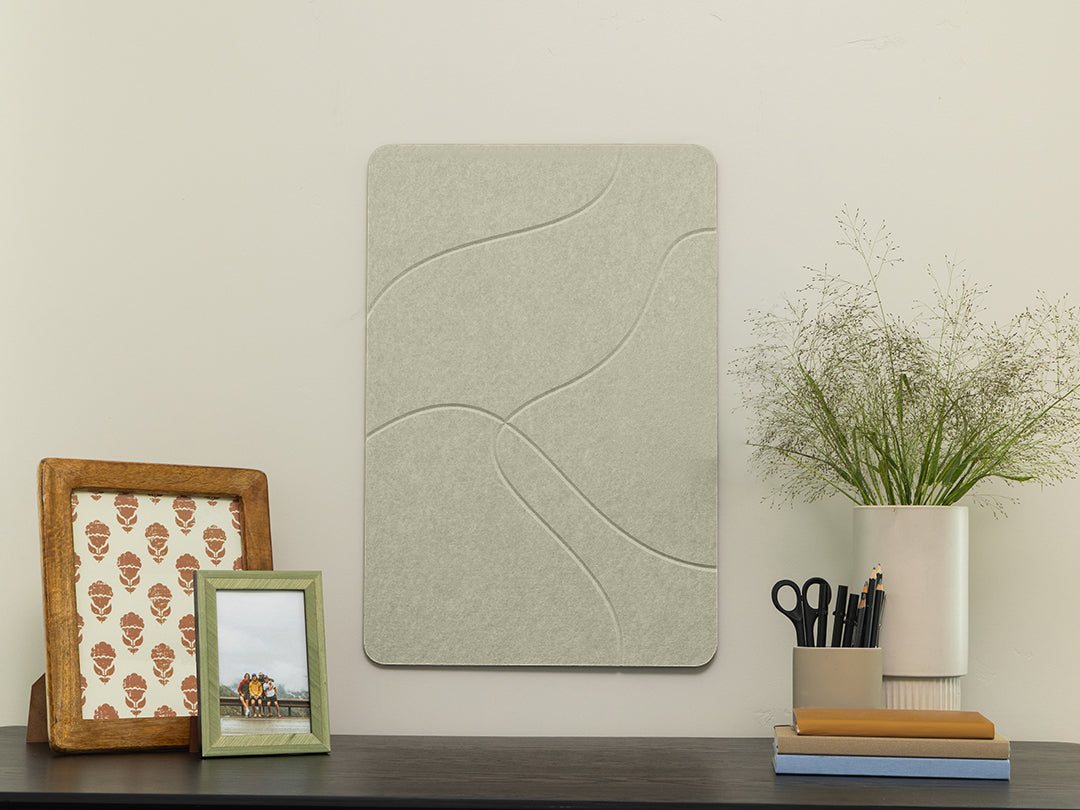 Decorative wall panel on a shelf with picture frames, plants, and stationery items.