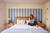 Felt Right wall art using shades of blue felt tiles to create a headboard behind a bed with a woman sitting on the bed
